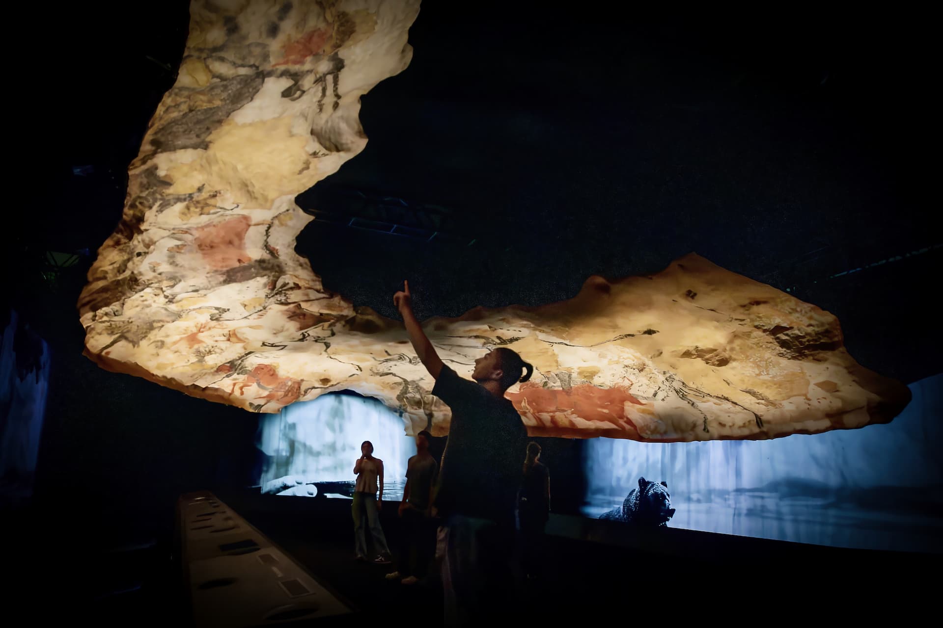 A visitor points up at the facsimile ceiling of the Hall of the Bulls