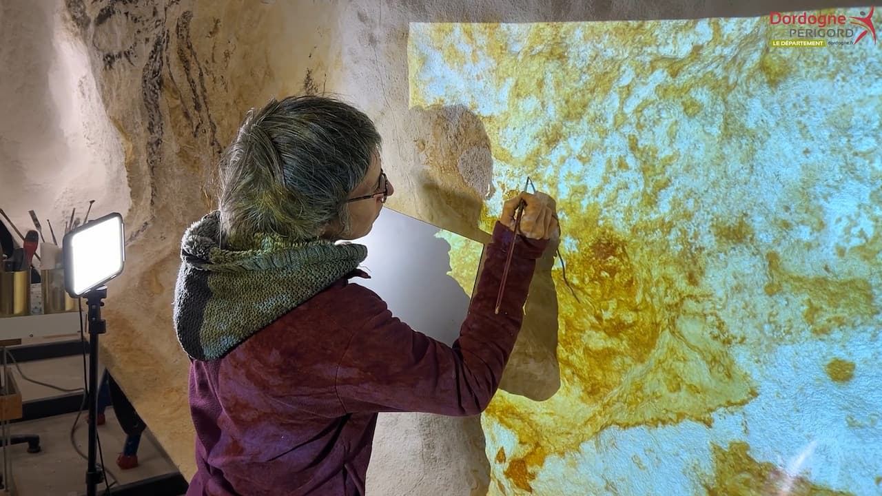 An artist painting the Hall of the Bulls facsimile at the Périgord Facsimile Workshop